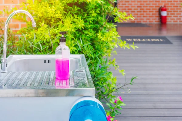 Pink alcohol gel bottle or antibacterial soap sanitizer on aluminum sinks in garden, Alcohol gel for cleaning hand to prevent the spread of germs and bacteria and avoid infections corona virus (covid-19)