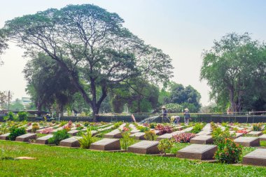 KANCHANABURI THAILAND - 21 Şubat: Kimliği belirsiz işçiler, 21 Şubat 2020 'de Kanchanaburi, Tayland' daki Kanchanaburi Müttefik Savaş Mezarlığı 'nda çiçek yenileyip dekore ediyorlar
