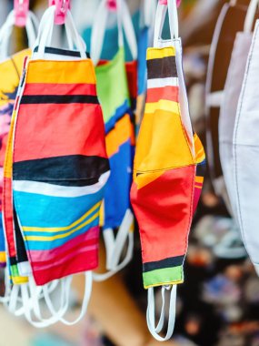 Sokak pazarında satılan mikropları (Covid-19) önlemek için moda kumaş pamuğundan yapılan el yapımı renkli maske çeşitliliğine yakın. Arkaplanda bulanıklık olan seçici odak.