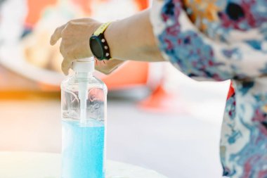 Kadın, şehirde elini temizlemek için el dezenfektanı şişesine basıyor. Grip virüsü, Covid-19 (Coronavirus hastalığı). Alkol jeli şişesine odaklan.