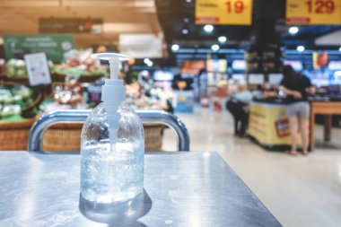 Corona virüsünün yayılmasını önlemek için el temizliği için alkol jeli şişelerini temizleyin (Covid-19). Süpermarketten almadan önce müşteriler için giriş servisini yerleştir.