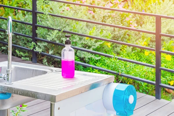 Pink alcohol gel bottle or antibacterial soap sanitizer on aluminum sinks in garden, Alcohol gel for cleaning hand to prevent the spread of germs and bacteria and avoid infections corona virus (covid-19)