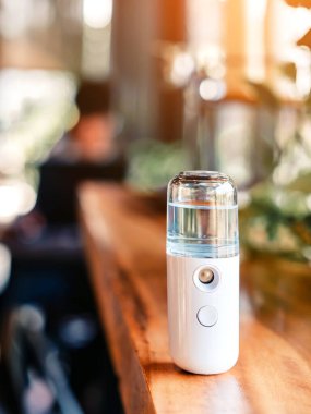 Corona virüsünün (Covid-19) kahve dükkanından almadan önce müşterilere hizmet etmek üzere masaya konmasını önlemek için el temizleme için alkol nano sis spreyi. Modern sağlık teknolojisi.