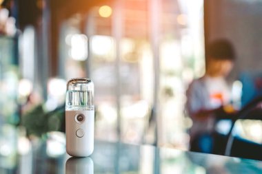 Corona virüsünün (Covid-19) kahve dükkanından almadan önce müşterilere hizmet etmek üzere masaya konmasını önlemek için el temizleme için alkol nano sis spreyi. Modern sağlık teknolojisi.