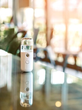 Corona virüsünün (Covid-19) kahve dükkanından almadan önce müşterilere hizmet etmek üzere masaya konmasını önlemek için el temizleme için alkol nano sis spreyi. Modern sağlık teknolojisi.