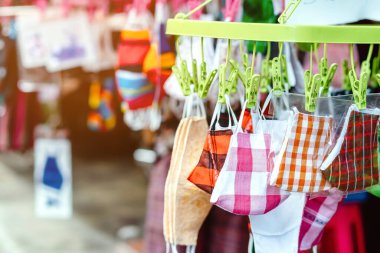 Sokak pazarında satılan mikropları (Covid-19) önlemek için moda kumaş pamuğundan yapılan el yapımı renkli maske çeşitliliğine yakın. Arkaplanda bulanıklık olan seçici odak.