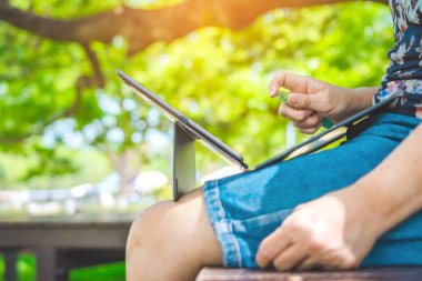 Kadın, virüsü ve bakterileri önlemek için dizüstünü temizleyen sprey alkol dezenfektanı kullanarak koruyucu maske takıyor. Coronavirus için karantina (Covid-19). Dizüstü bilgisayarı sprey alkolle temizleme