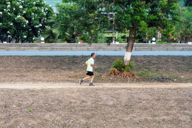 KANCHANABURI / THAILAND-MAY 7. 2020: Tayland 'ın Kanchanaburi kentinde 7 Mayıs 2020 tarihinde Mae Klong Barajı' ndaki sulama kanalının yanında sağlıklı bir yolda koşan tanımlanamayan Taylandlı sporcular.