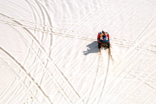 Tourist enjoy riding the quad bike or powerful fast off-road four-wheel drive ATVs at white sand dunes in Mui Ne, Vietnam.