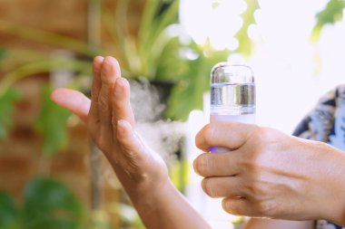Coronavirus salgını sırasında ellerine antiseptik sprey sıkan kadın. El dezenfektan spreyi kullanıyor. Modern sağlık teknolojisi kavramı. Yeni normal yaşam tarzı..