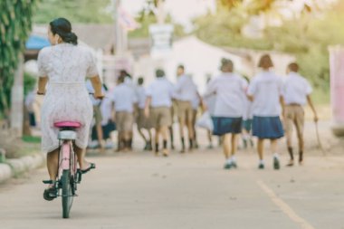 Öğrencilere ders vermek için bisiklet süren bayan öğretmenin bulanık görüntüsü.