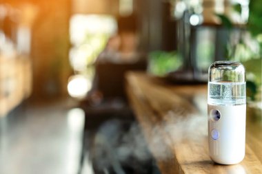 Corona virüsünün (Covid-19) kahve dükkanından almadan önce müşterilere hizmet etmek üzere masaya konmasını önlemek için el temizleme için alkol nano sis spreyi. Modern sağlık teknolojisi.