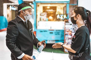 KANCHANABURI, THAILAND - NİSAN 28,2020: Kimliği belirsiz erkek memur, insanlarda koronavirüs ya da Robinson Mağazası 'ndaki COVID-19 salgını olarak termometre tarama sıcaklığını kullanıyor.