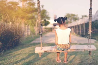 Salıncakta sallanan genç kızın arkası görünüyor. Annesini organik üzüm çiftliğinde bekliyor..
