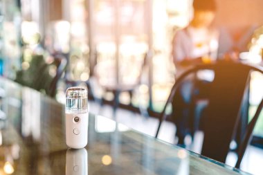 Corona virüsünün (Covid-19) kahve dükkanından almadan önce müşterilere hizmet etmek üzere masaya konmasını önlemek için el temizleme için alkol nano sis spreyi. Modern sağlık teknolojisi.