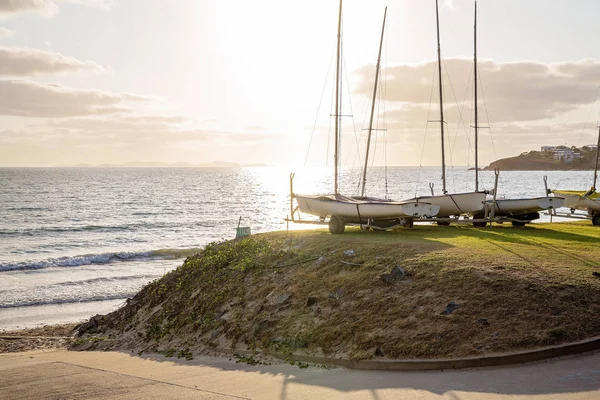 Vroege ochtend zonlicht schijnt aan de overkant van de oceaan op geparkeerde zeilboten — Stockfoto