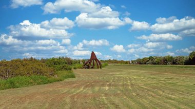 Mackay, Queensland, Avustralya - Şubat 2020: Bulutlu mavi bir gökyüzünün altında nehir kıyısında biçilmiş parktaki bir mangrov tohumunu temsil eden çelik bir heykel