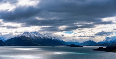 Bulutların arasından geçen güneş Yeni Zelanda Wakatipu Gölü 'nün dramatik bir manzarasını oluşturuyor.