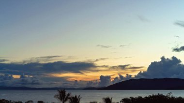 Şafağın altın ışığı bulutlardan süzülüyor ve okyanusta parlıyor.