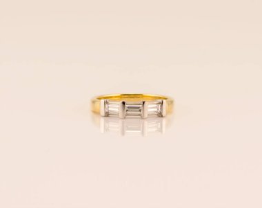 A modern diamond wedding band created with three baguette diamonds set in yellow gold, isolated on a white background clipart