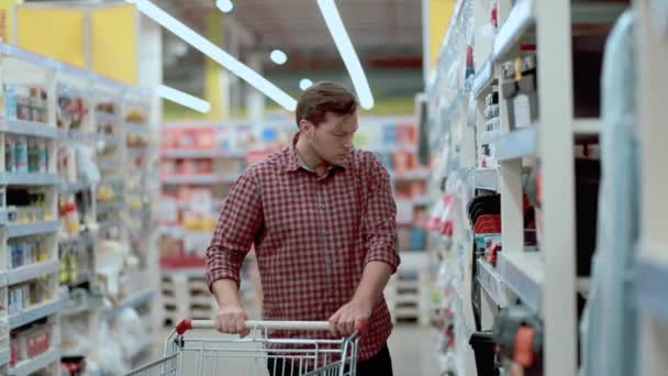 Un homme dans un magasin avec un panier sélectionne des marchandises — Video