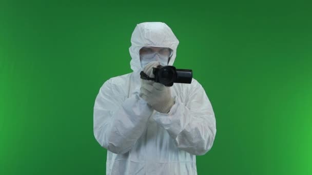 En un traje de protección y máscara está grabando en una videocámara — Vídeo de stock