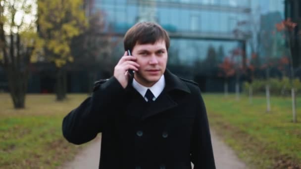 Επιχειρηματίας που περπατάει στο πάρκο και μιλάει στο τηλέφωνο. — Αρχείο Βίντεο