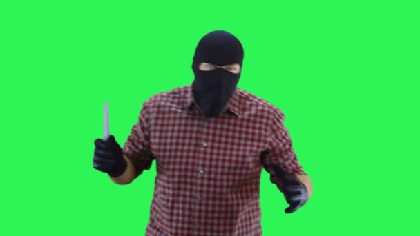 Чоловік в чорній масці і плетена сорочка в руках тримає ніж йде вперед хоче атакувати, на зеленому тлі — стокове відео
