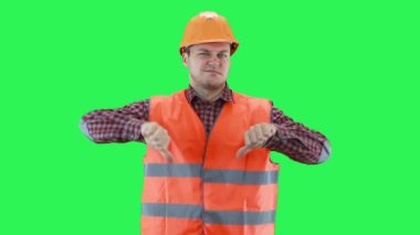 İnşaat miğferi ve turuncu yelek giyen adam her şeyin kötü, yeşil ekran arka planı olduğunu elleriyle gösteriyor.