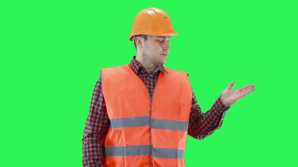 Man in a construction helm and orange vest hand shows a choice, green screen background, copy space — Stok Video