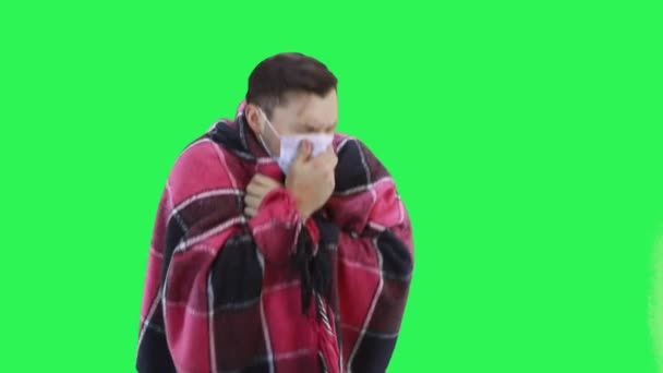 Chory mężczyzna owinięty w koc kaszle w maskę ochronną, zielone tło ekranu — Wideo stockowe