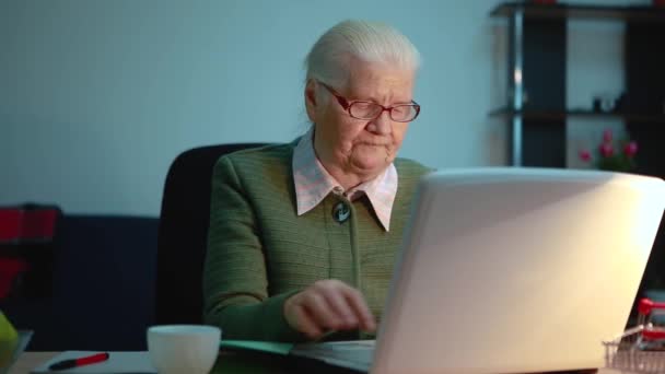 Een oudere vrouw kijkt in een laptop monitor tijdens het werken aan het. — Stockvideo