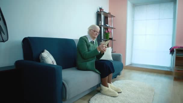 Reife Frau sitzt auf einem Sofa zählt Geld — Stockvideo