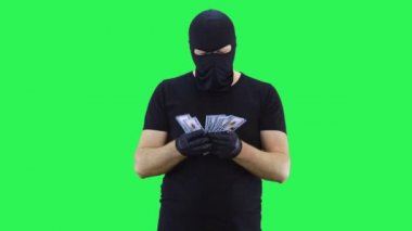 Maskeli adam parayı sayıyor. Kar maskesi. Yeşil perde geçmişi..