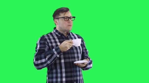 Een jonge man in een geruit shirt luistert aandachtig en knikt met zijn hoofd en drinkt koffie, kijkt weg — Stockvideo
