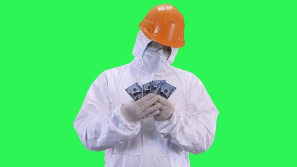 Un hombre en un casco y traje de protección cuenta money.Green fondo de pantalla . — Vídeos de Stock