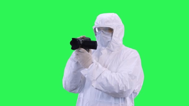 Un hombre con un traje de protección y gafas es la grabación de vídeo en cámara lenta en una cámara de vídeo.Fondo de pantalla verde . — Vídeos de Stock