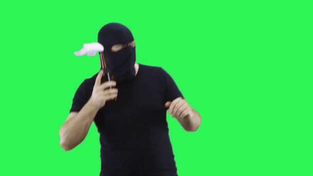 A man in a black mask holds a bottle with a prosperous mixture in his hand, swings for a throw.Balaclava.Green screen background. — Stock Video