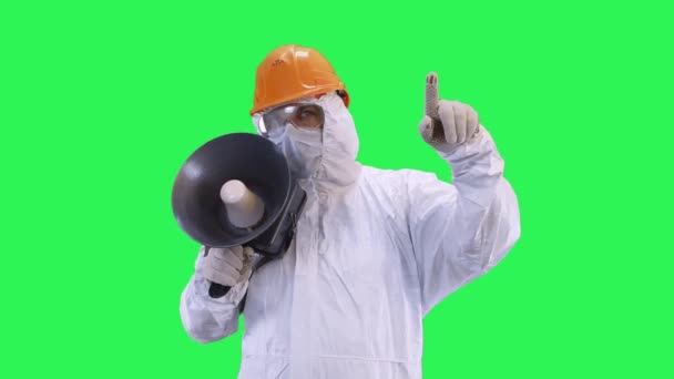 Un hombre con un casco y traje protector habla en un grito mostrando su mano a la parte superior.Fondo de pantalla verde . — Vídeo de stock