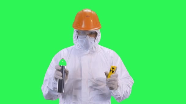 Un homme dans un casque et une combinaison de protection pulvérise à partir d'une canette de pulvérisation.Fond d'écran vert . — Video