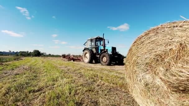 Traktor pracuje v terénu, sklízecí zařízení pracuje na poli. — Stock video