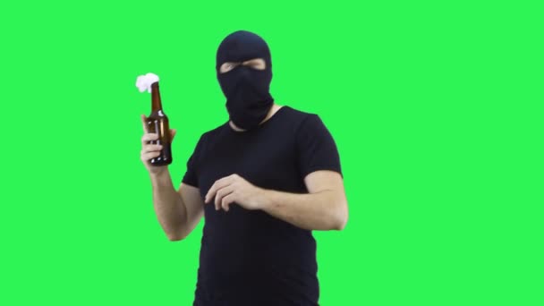 Человек в черной маске держит бутылку с благополучной смесью в руке, смотрит, где бросить его.Balaclava.Green фона экрана . — стоковое видео