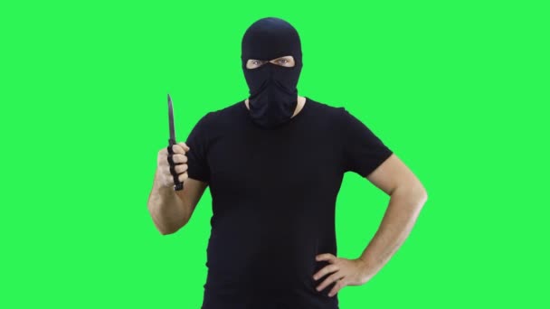 Ένας άνθρωπος σε μια μαύρη μάσκα κρατά ένα μαχαίρι στο χέρι του.Balaclava.Green φόντο οθόνη. — Αρχείο Βίντεο