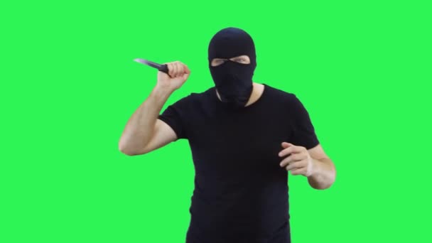 Чоловік у чорній масці тримає в руці ніж йде вперед. Балаклава. Зелений фон екрану . — стокове відео