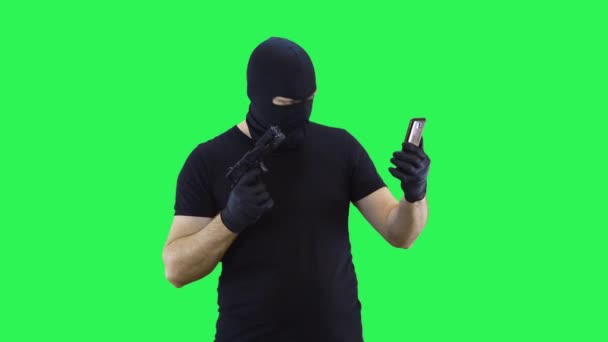 Um homem em uma balaclava falando via vídeo chamando em um smartphone, fundo de tela verde . — Vídeo de Stock