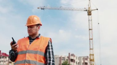 İnşaatçı inşaat alanının arka planında radyoda konuşuyor..