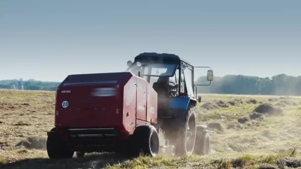 Mezőgazdasági gépek pótkocsival feldolgozza a mezőket.A terepen működik a betakarító berendezés.A traktor terepen közlekedik.. — Stock videók