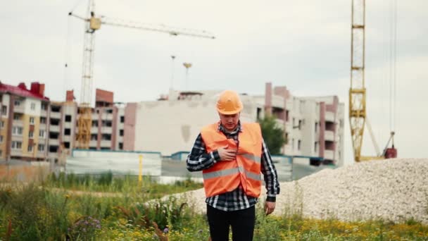 Un homme en gilet orange et une orange s'accrochent à un cœur avec une crise cardiaque sur un chantier de construction . — Video