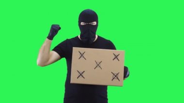 Siyah maskeli bir adam yürüyüş için bir tabela tutuyor, isteklerde bulunuyor, yeşil ekran arka planı
