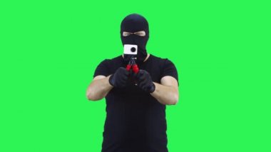 Kar maskeli bir adam yeşil ekran arka planda bir kamera alır.